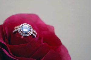 close up shot of diamond ring sitting within the petals of a red flower